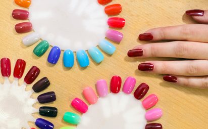 Woman choosing which color of fake nails to apply at the salon.