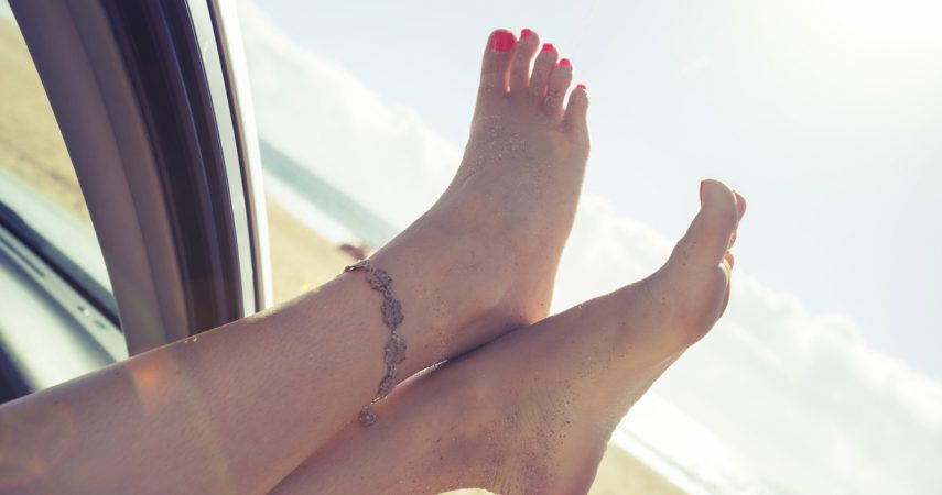 Summer nail polish on toes sticking out a car window.
