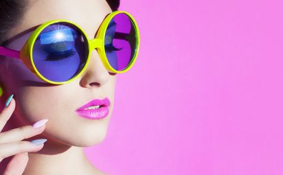 Young woman wearing fun sunglasses and purple lip products.