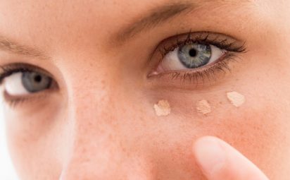 woman applying concealer to show how to cover dark circles