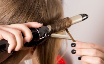 A woman using a curling iron on her hair