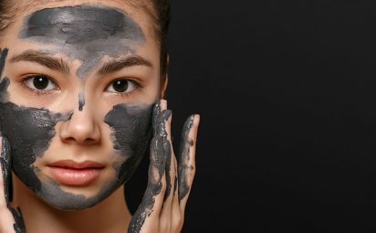 A woman is applying a charcoal face mask