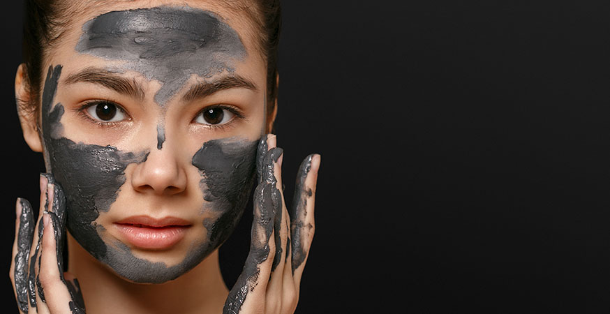 A woman is applying a charcoal face mask