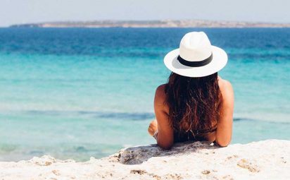 A woman sitting on the beach, soaking up some sun.