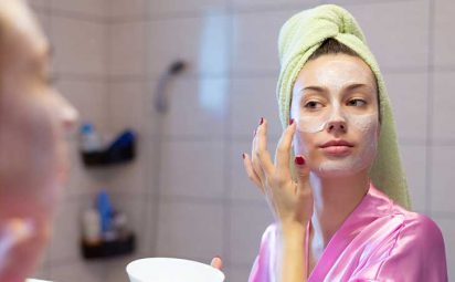 A woman applying cream to her face.