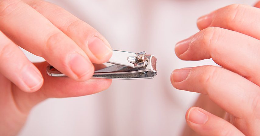 A woman is trimming her nails with a nail clipper