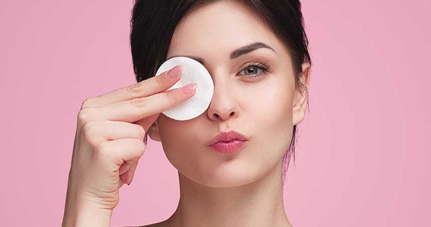 A woman using a cotton pad to remove her makeup