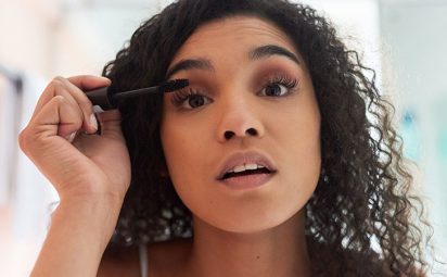 A woman is applying mascara to her lashes