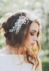 brunette woman with white floral headband and loose curls