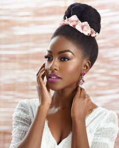 black woman in white dress has fancy updo with pink floral accessories