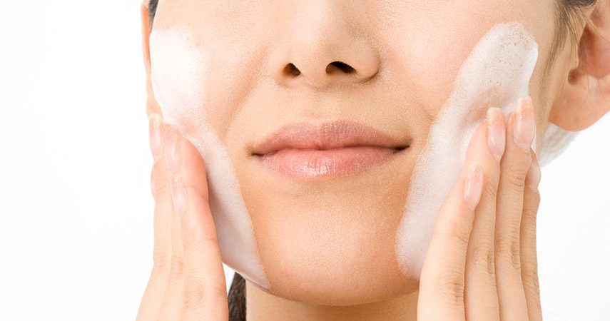 Woman is washing her face with a cleanser