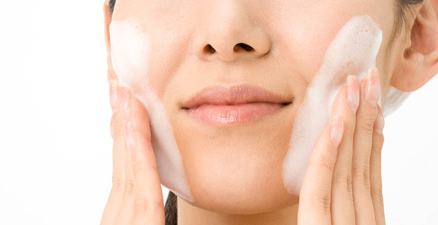 Woman is washing her face with a cleanser
