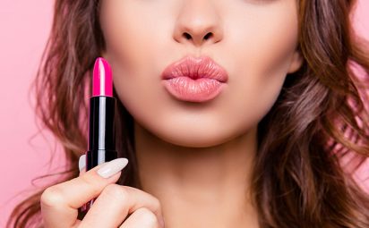 A woman is holding lipstick and puckering her lips