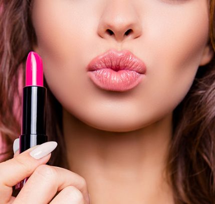 How to Choose the Right Lipstick Color for Your Skin Tone A woman is holding lipstick and puckering her lips