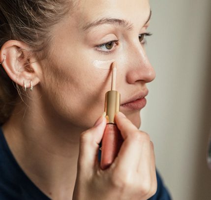 woman applying liquid concealer under eye