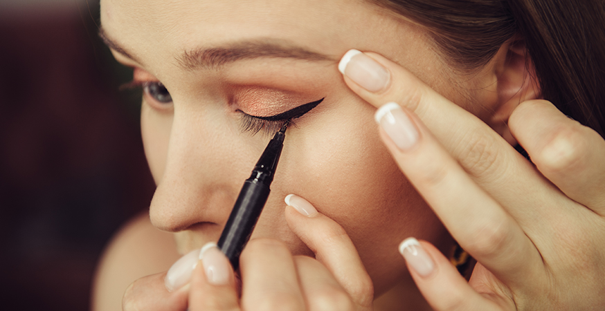 a woman applying black liquid eyeliner