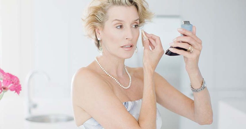 mature woman applying makeup with a beauty sponge