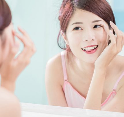 Best Eyelash Growth Serum: Discover the Best Option for You asian woman touching eyelashes while looking in mirror