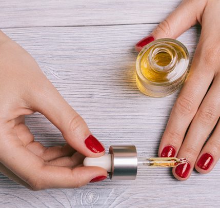 Dry Cuticles: How to Prevent & Treat Dry Cuticles woman with red painted finger nails putting oil on cuticles