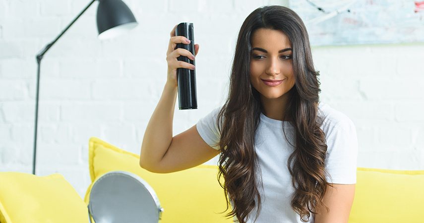 woman applying spray to hairstyle