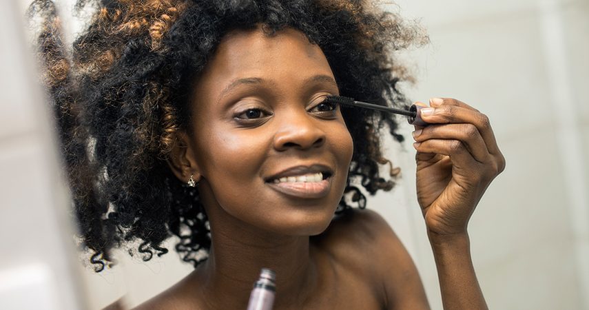 black woman applying mascara in a mirror