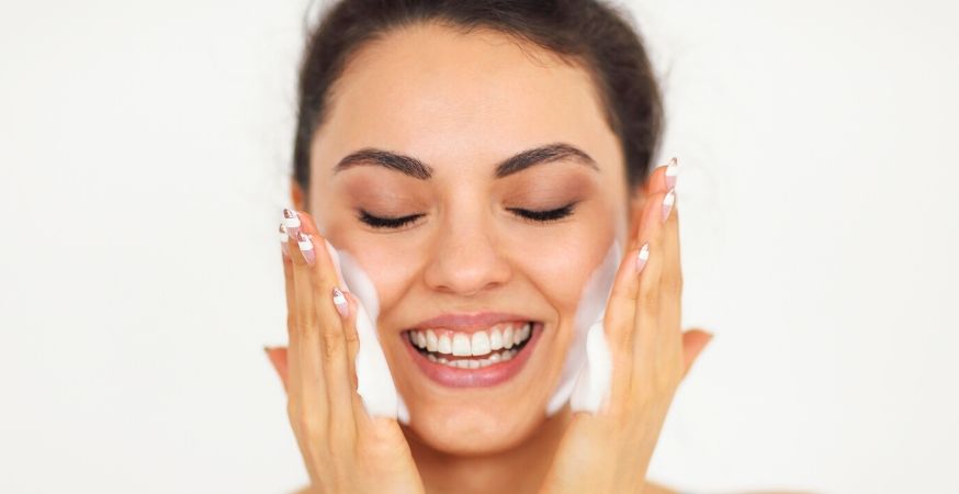 A girl washing her face with a cleanser that is good for sensitive skin.