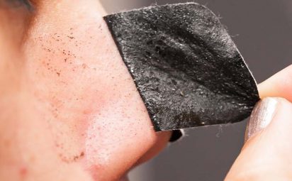 Someone using a charcoal pore strip to remove blackheads.