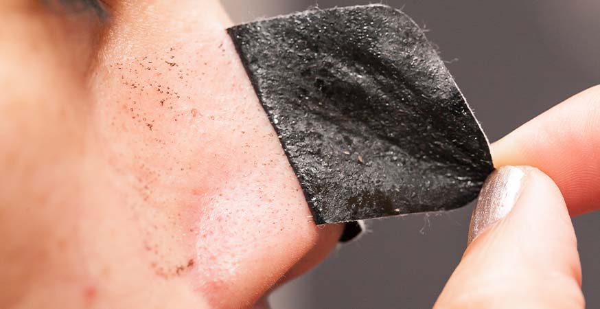Someone using a charcoal pore strip to remove blackheads.