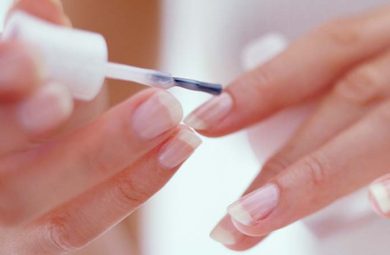 Someone applying nail growth nail polish to their nails.