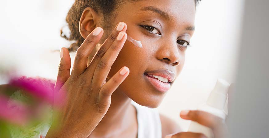 A woman applying SPF sun cream to her face.