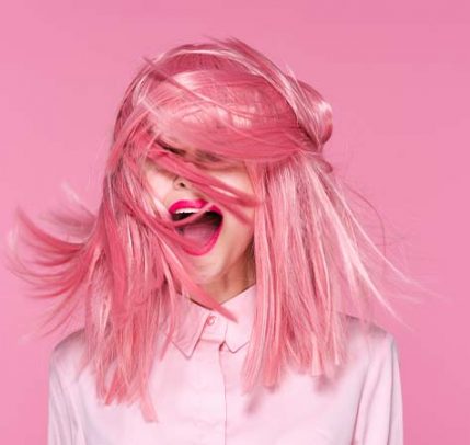 Best shampoo for color treated hair Someone standing in front of a pink background with pink hair.