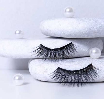 How to apply magnetic lashes Black fake eyelashes against white cotton pads.