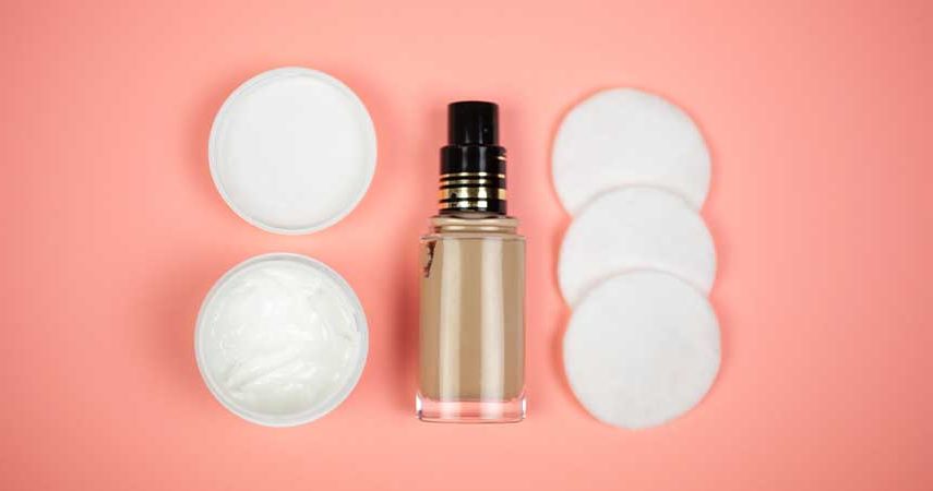 A bottle of BB cream and cotton makeup pads against a peach background.