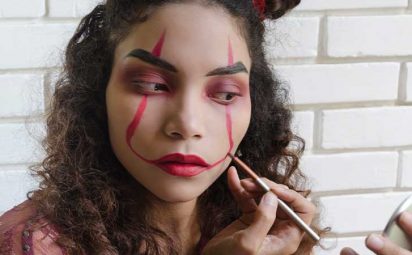 A girl painting her face with red makeup.