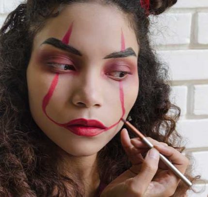 Easy Halloween makeup ideas A girl painting her face with red makeup.