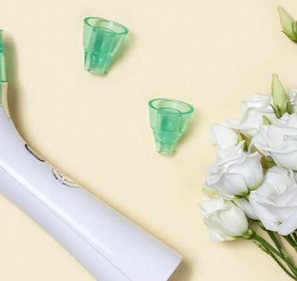 blackhead suction tool An image of a blackhead suction tool with two replacement tips laying next to white flowers.