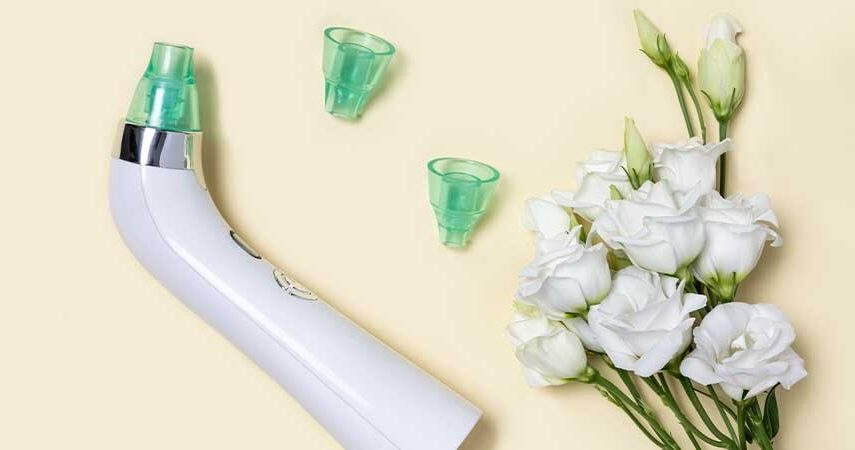 An image of a blackhead suction tool with two replacement tips laying next to white flowers.