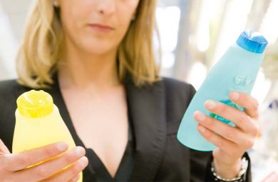A woman holding two different shampoos.