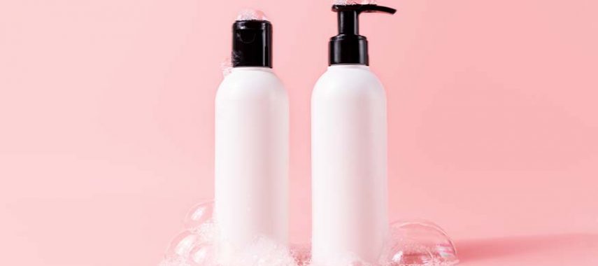 A shampoo and conditioner bottle against a pink background.