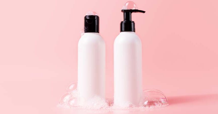 A shampoo and conditioner bottle against a pink background.